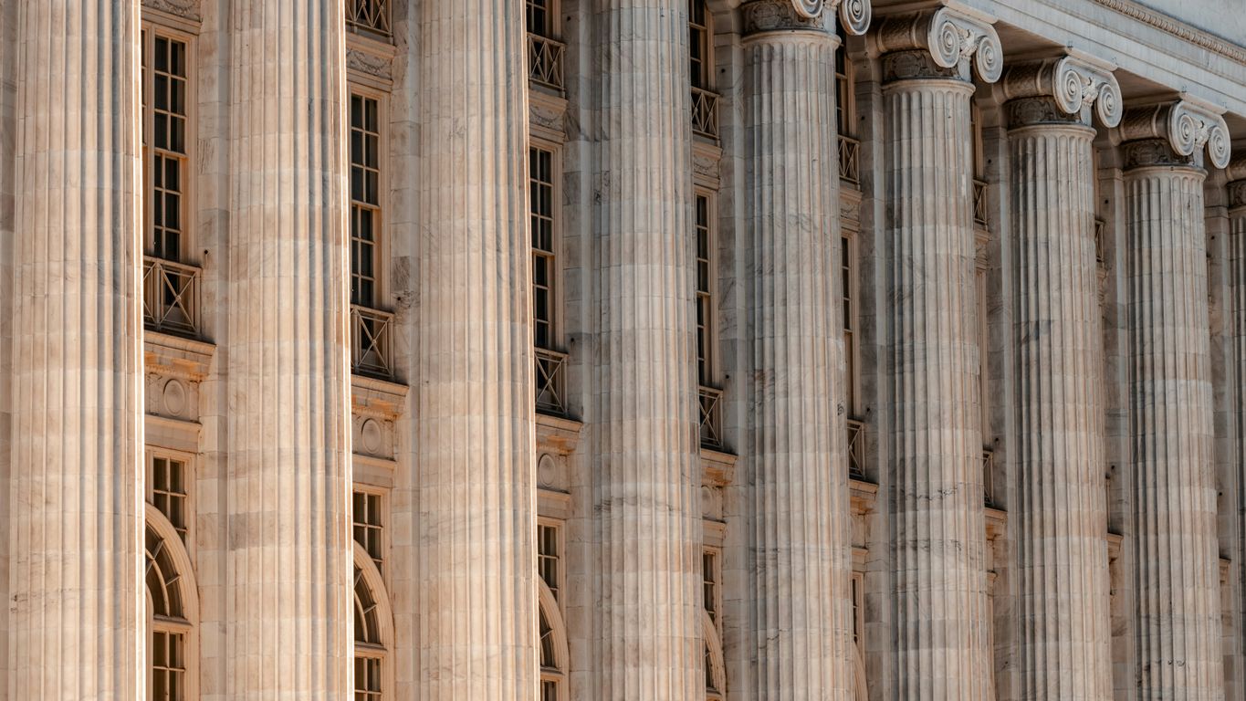 a large building with columns and a clock on the front of it