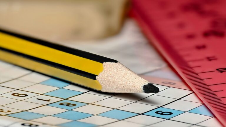 A pencil sitting on top of a crossword puzzle
